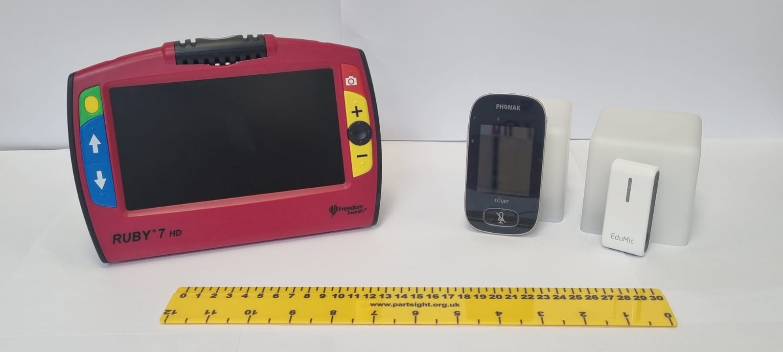 In the image there is a magnifier, 2 radio aids and a visual impairment ruler.